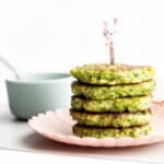 Stack of Broccoli Fritters on Plate with Dip in Background.